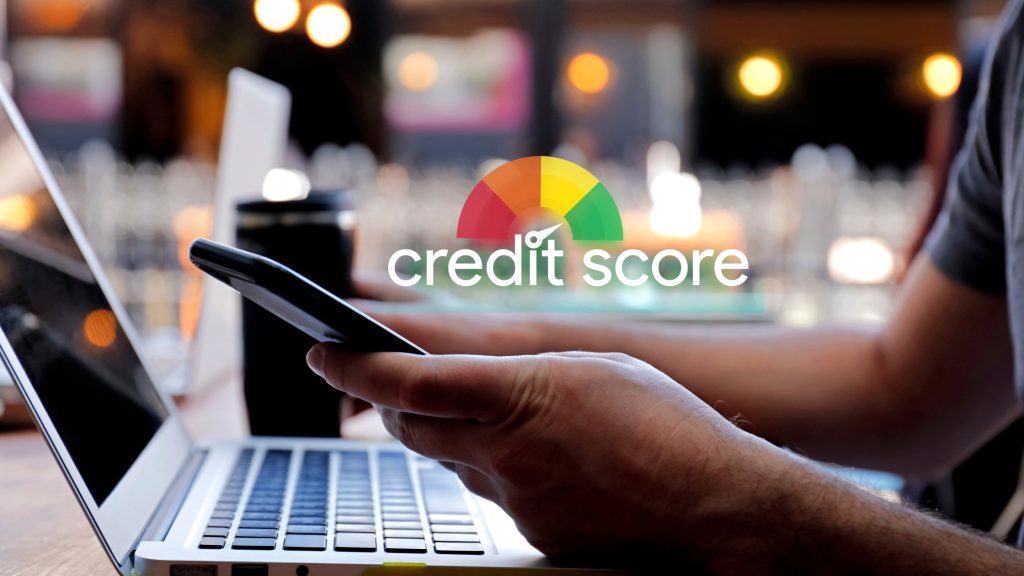 Person checking credit score on smartphone and laptop
