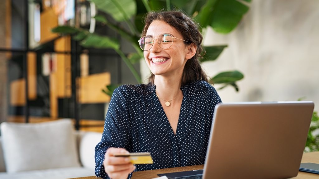 Smiling woman shopping online with credit card and laptop