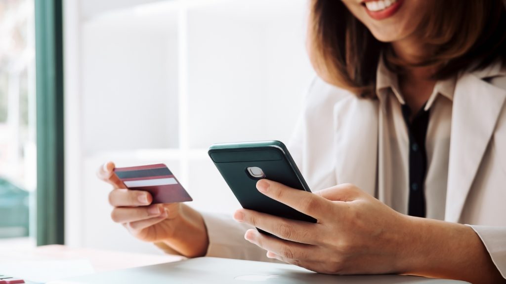 Woman making online payment using smartphone and credit card