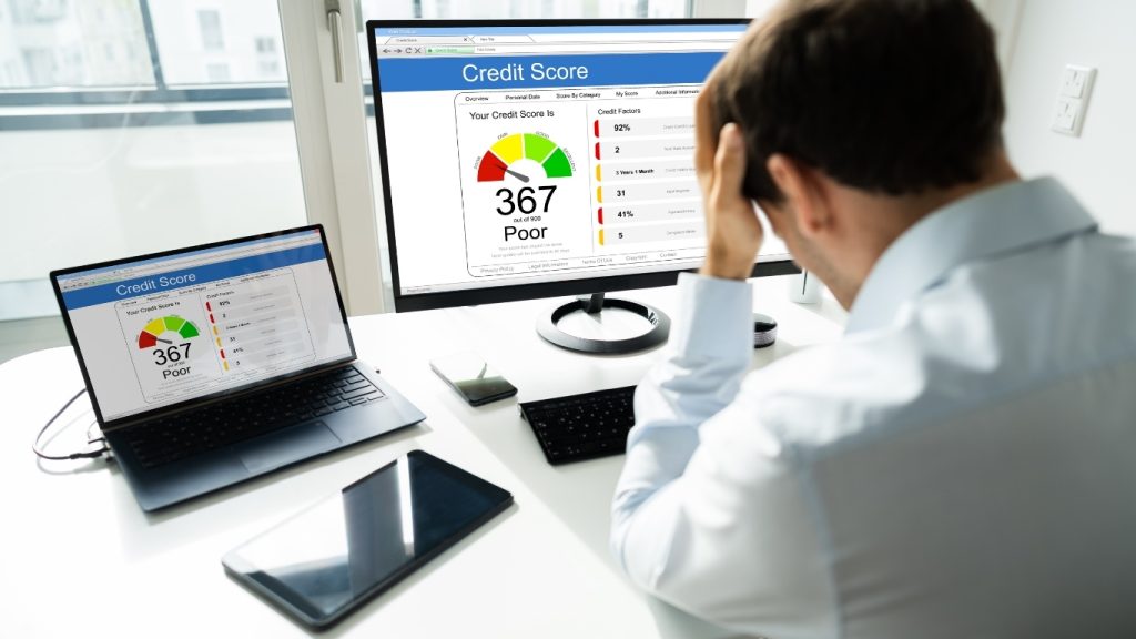 Frustrated man looking at poor credit score on computer screen