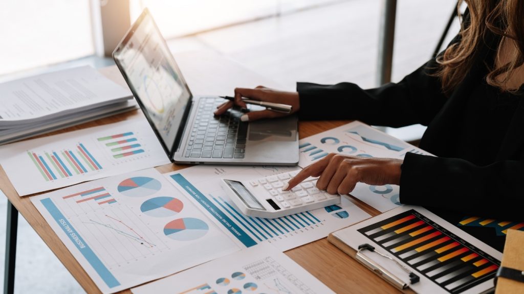 Businesswoman reviewing financial charts and calculating data on office desk
