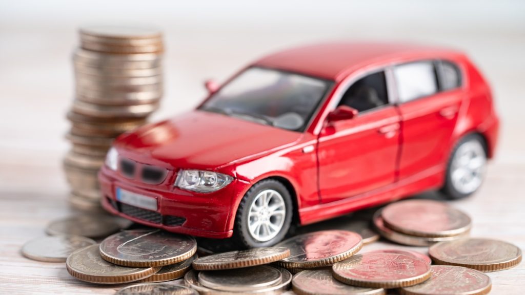 Car loan concept with red toy car and stacked coins