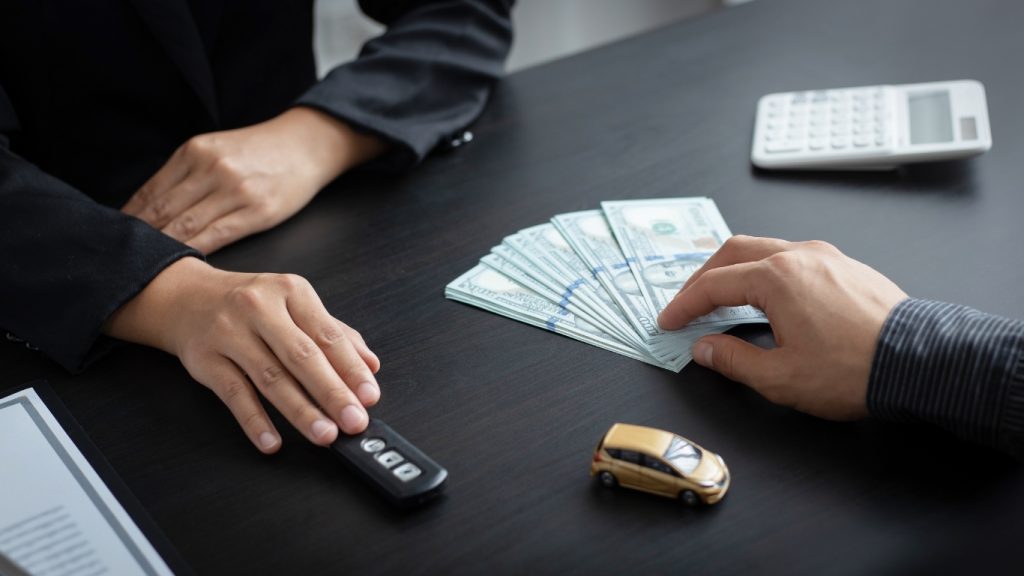Car loan payment with cash and car key exchange at dealership