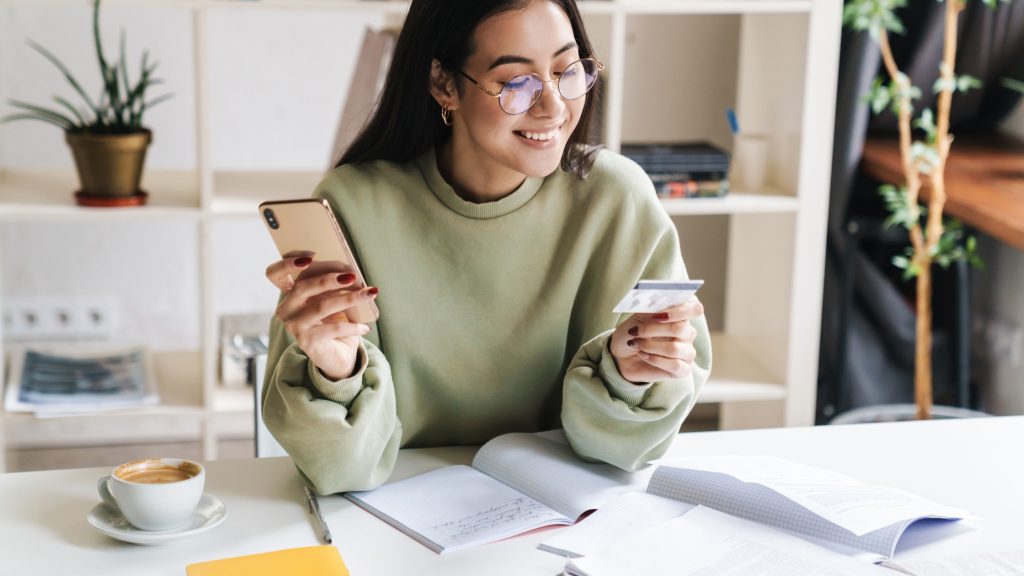 Joyful woman celebrating successful online payment with credit card and laptop.