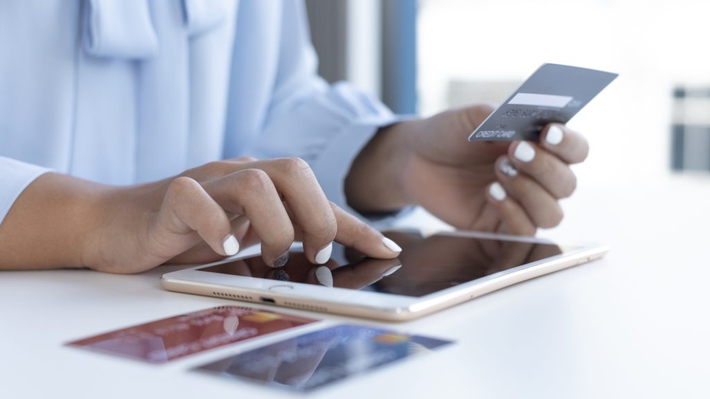 Woman using tablet and holding credit card for secure online payment or banking.