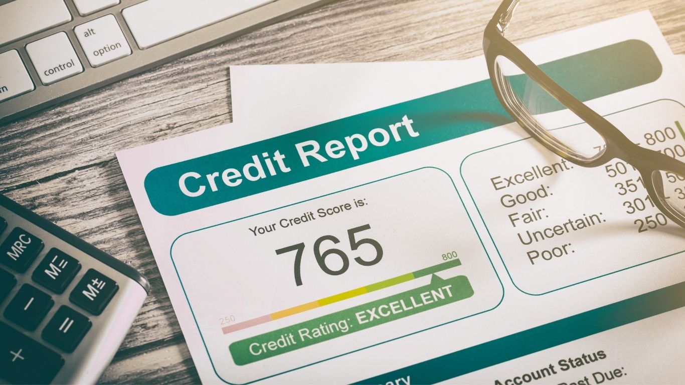 Credit report with a score of 765 labeled as excellent, next to calculator, keyboard, and glasses