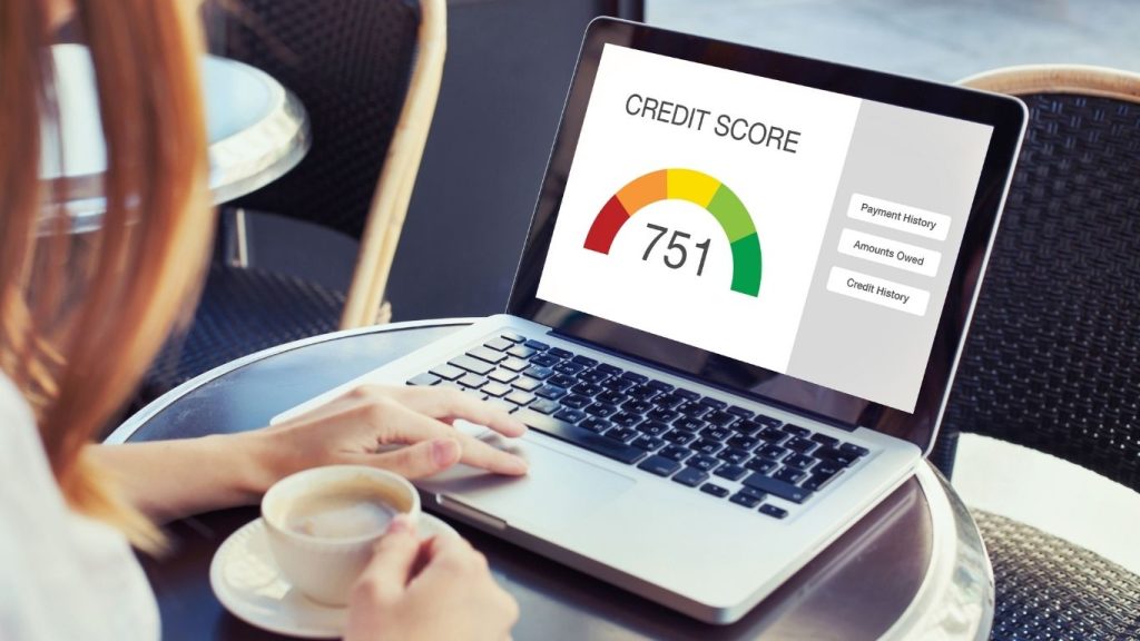 Person checking credit score on laptop while holding a coffee cup