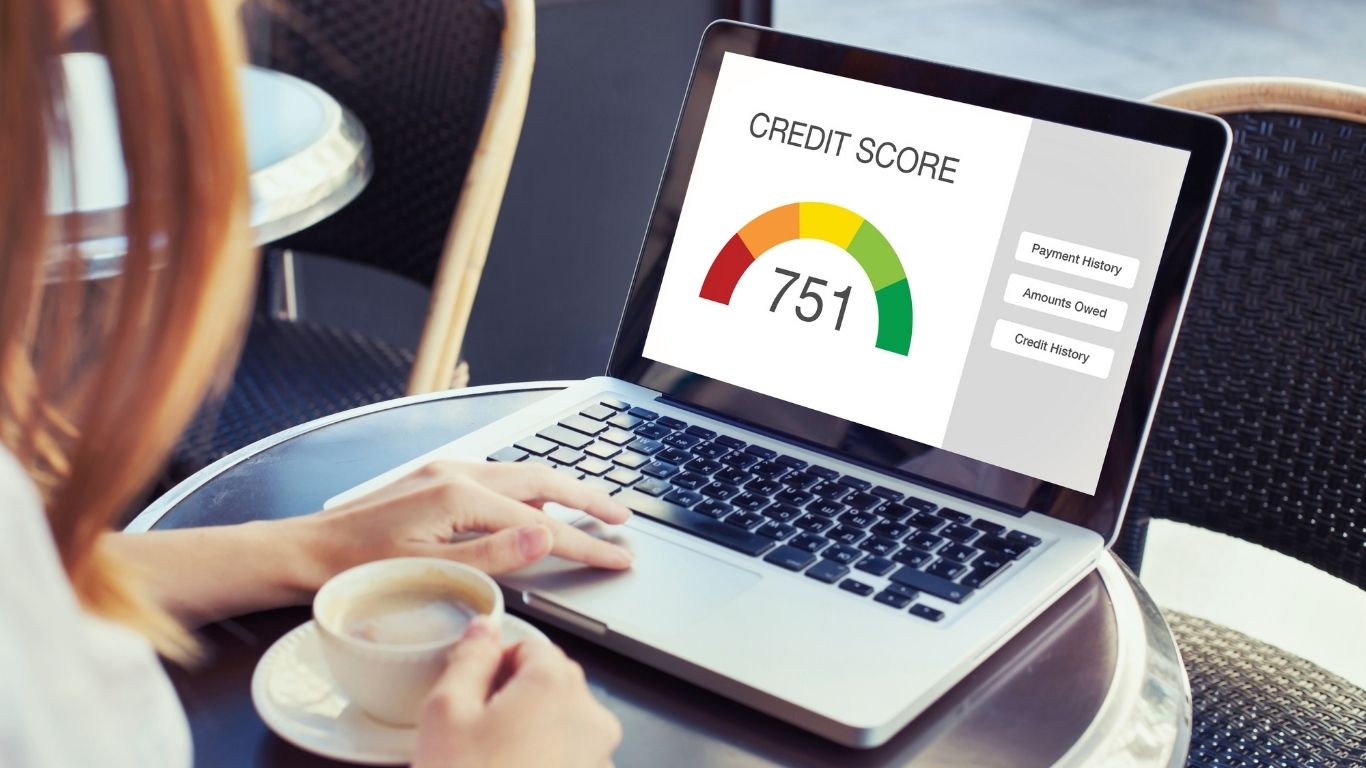 Person checking credit score on laptop while holding a coffee cup