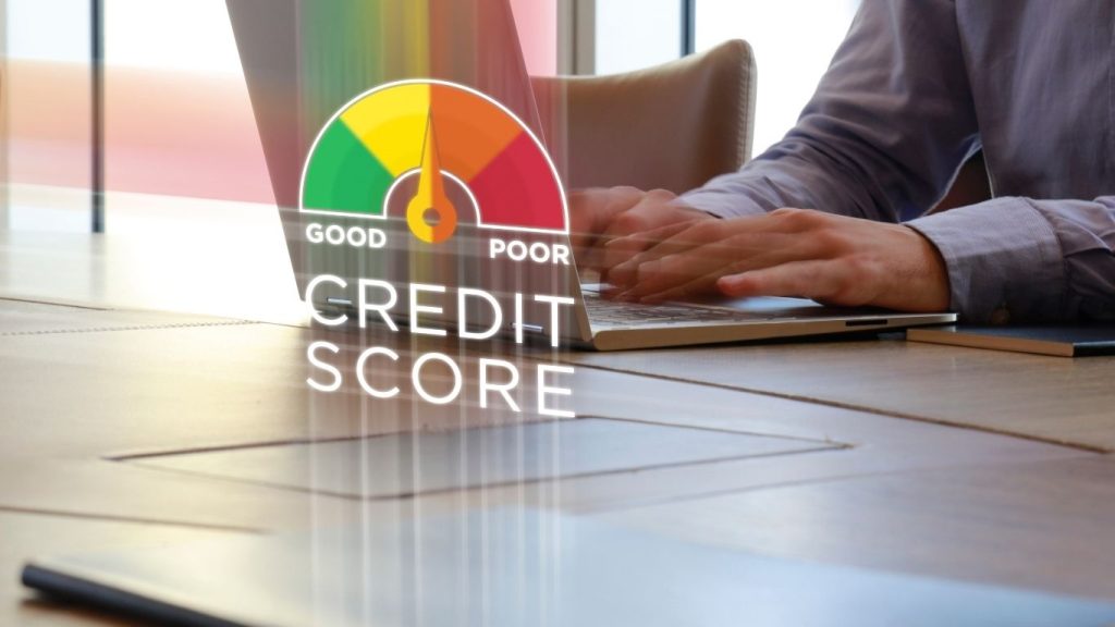 Person typing on a laptop with a virtual credit score gauge showing a poor to good range