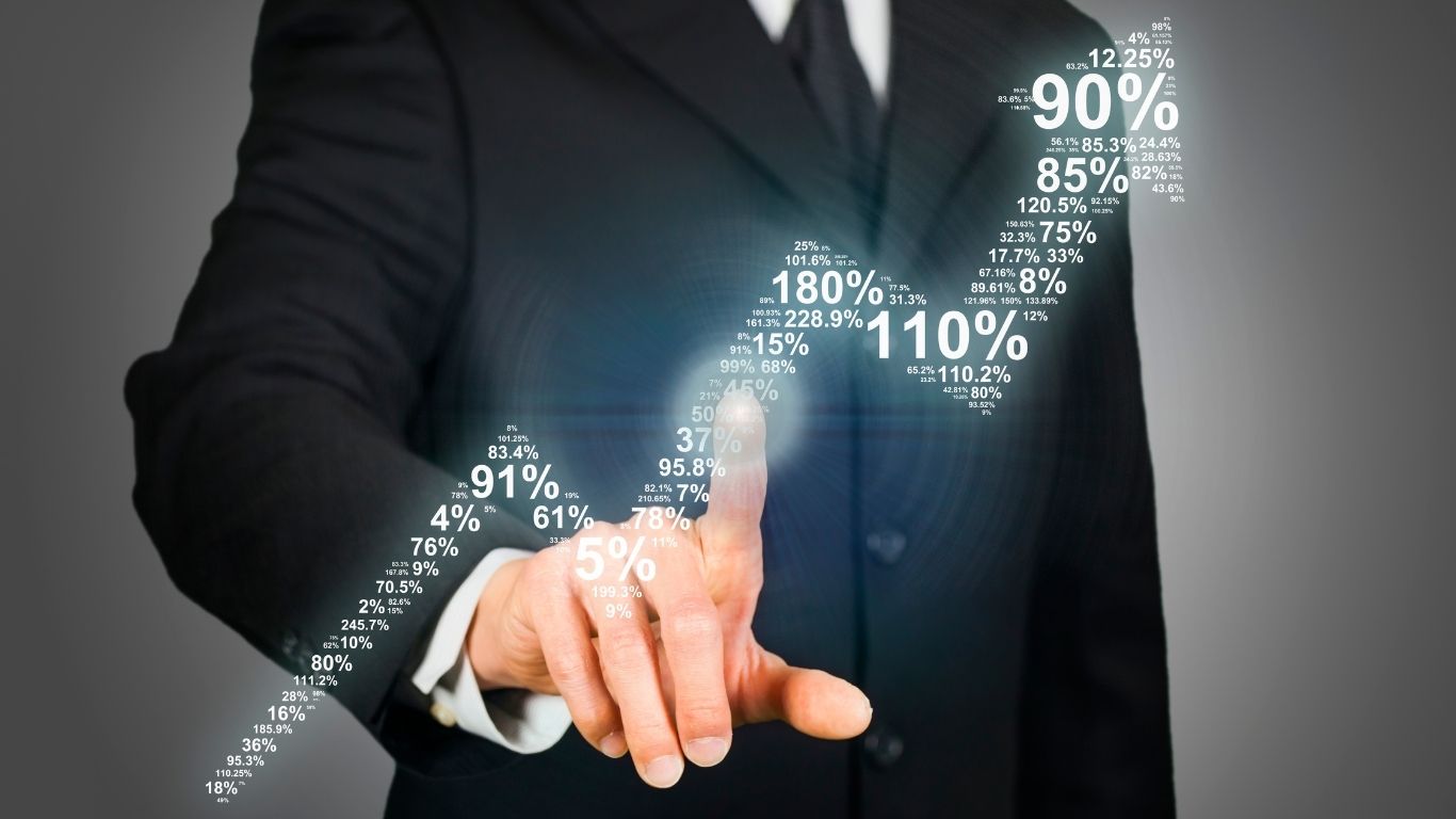 Businessman in suit interacting with virtual graph showing rising percentages, symbolizing financial growth.