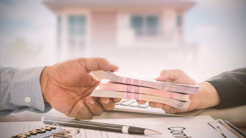 Hands exchanging money over financial documents and contract, symbolizing loan approval or financial transaction.