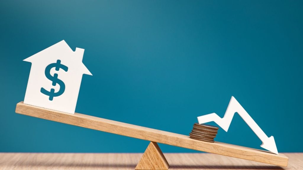 Real estate value imbalance concept, featuring a house and a falling market graph on a seesaw, with coins.How to fix a low credit score.
