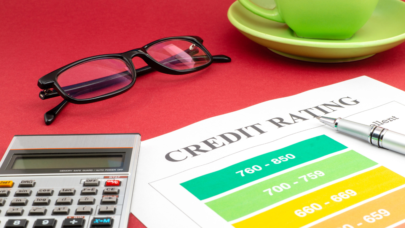 Credit rating report with calculator, eyeglasses, and coffee cup on red desk — financial planning concept.