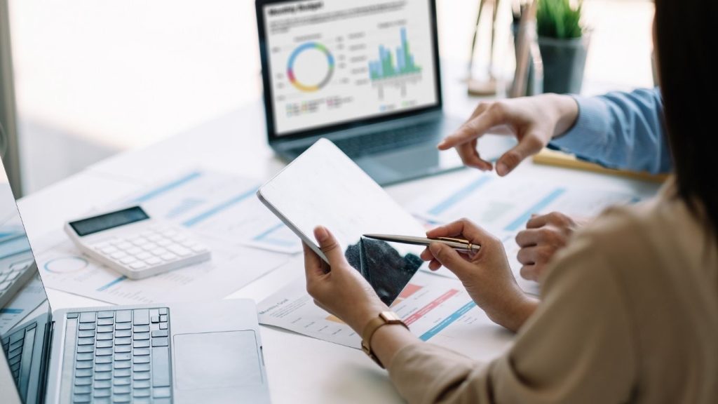 Two professionals reviewing financial data with documents, graphs, and a calculator during a credit consultation session.