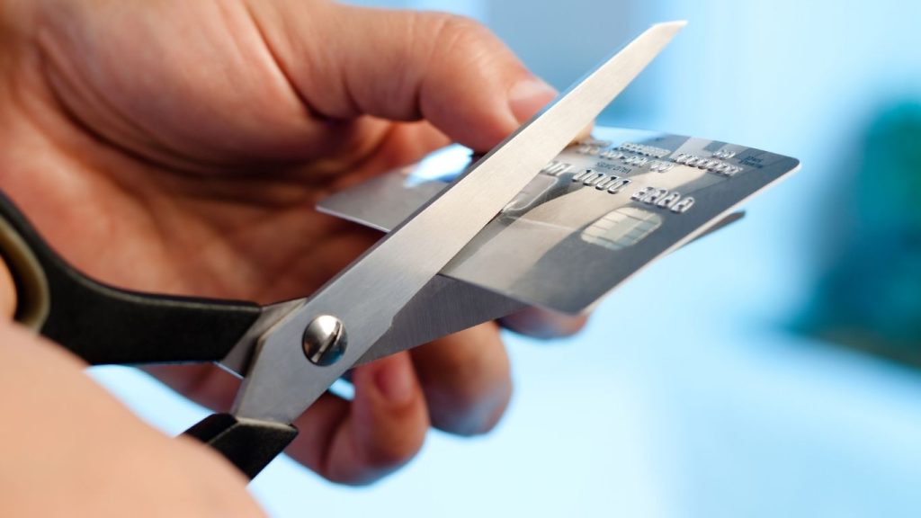 A person cutting a credit card with scissors, symbolizing the end of poor credit habits and a fresh financial start.