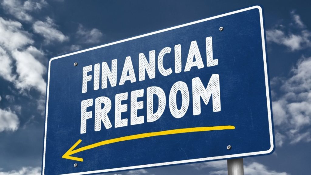 A blue road sign with the words “Financial Freedom” and a yellow arrow pointing left, set against a cloudy sky background.
