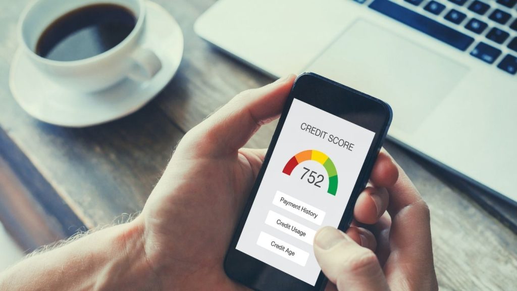 Hand holding smartphone showing high credit score of 752 on screen