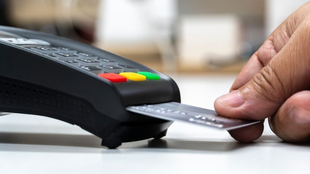 A close-up of a person's hand inserting a credit card into a payment terminal for a transaction.